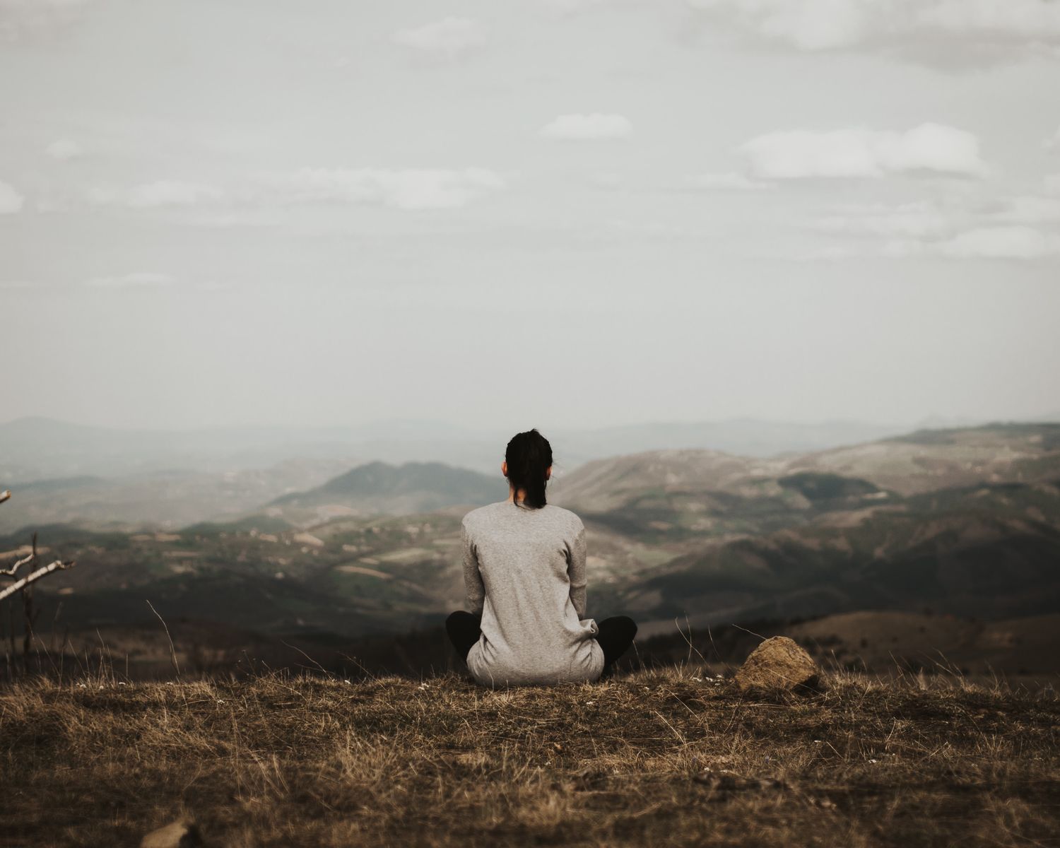 Woman sitting in nature with mountains on horizon